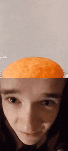 a close up of a person 's face with an orange in the background