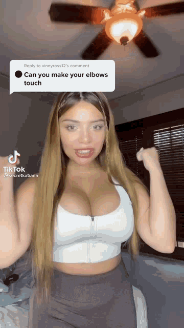 a woman with a lot of breasts is flexing her muscles in a room with a ceiling fan .