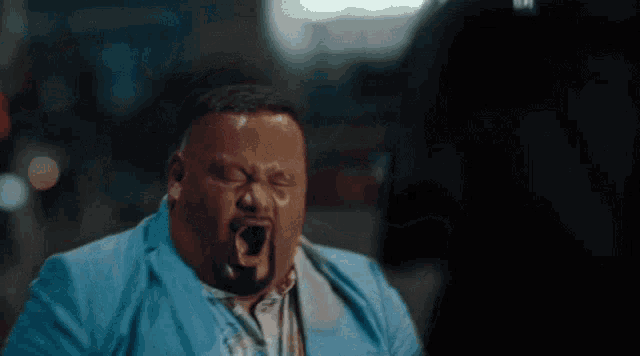 a man with a beard wearing a blue jacket making a funny face