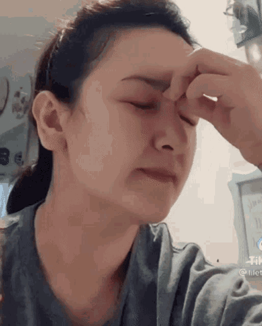 a woman is taking a selfie with her eyes closed and her hand on her forehead .
