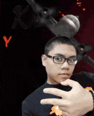 a man wearing glasses is making a peace sign in front of a sign that says k and y