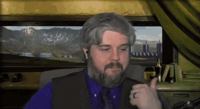 a man with a beard is giving a thumbs up in front of a painting