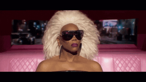 a woman wearing sunglasses and a white wig is sitting in a pink car