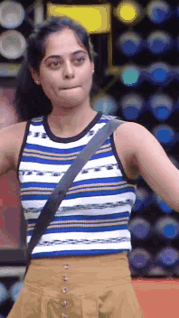 a woman wearing a striped tank top and a brown skirt is standing in front of a stage .