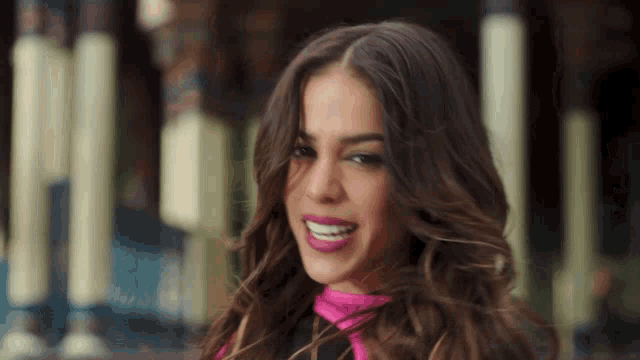 a woman wearing a pink scarf smiles for the camera