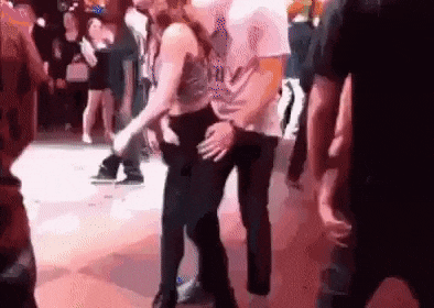 a man is touching a woman 's butt while dancing on a dance floor at a party .