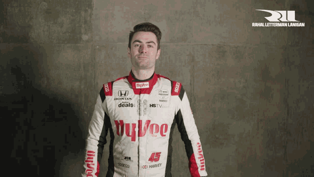 a man in a honda racing suit stands in front of a concrete wall