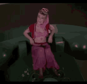 a woman in a pink dress is sitting on a telephone and giving a thumbs up .