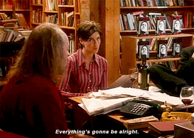a woman in a red shirt says " everything 's gonna be alright " while sitting at a desk