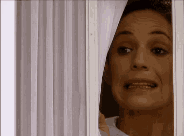 a woman is peeking out of a window with her mouth open