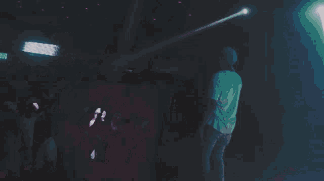 a crowd of people dancing in a dark room with a green exit sign