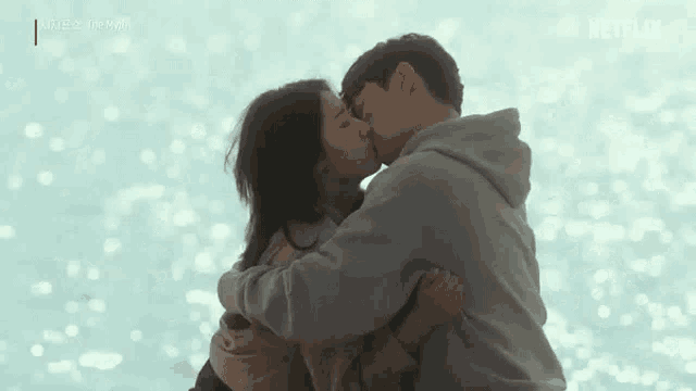 a man and a woman are kissing on a beach .