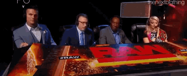 a group of people are sitting at a table with a sign that says raw .
