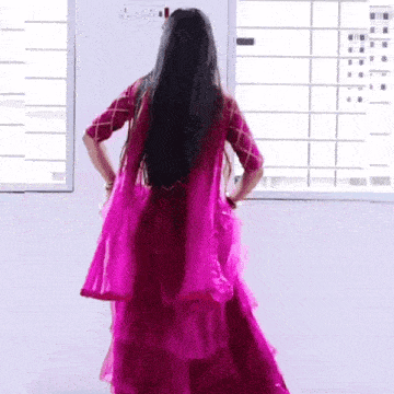 a woman in a pink dress stands in front of a window