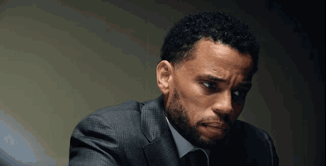 a man with curly hair and a beard wearing a suit and tie