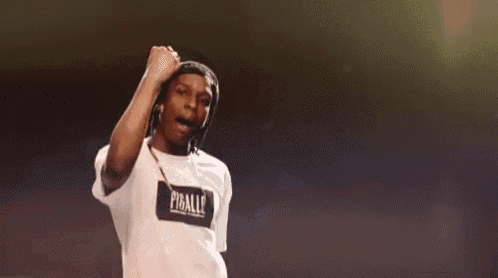a man in a white shirt is singing into a microphone while dancing on a stage .
