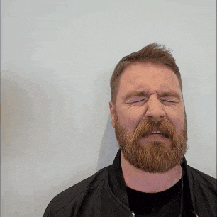 a man with a beard and a black jacket is making a funny face