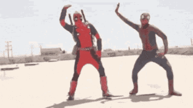 deadpool and spider-man are standing next to each other on a beach .