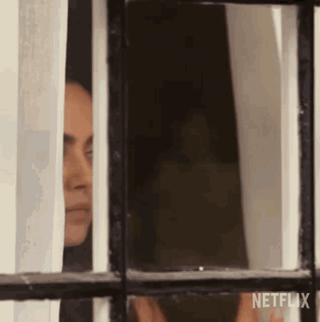a man is peeking out of a window with a netflix logo behind him .