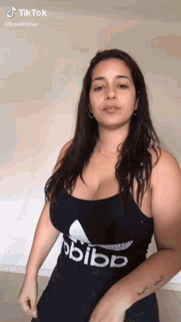 a woman with a tattoo on her arm is wearing a black adidas tank top