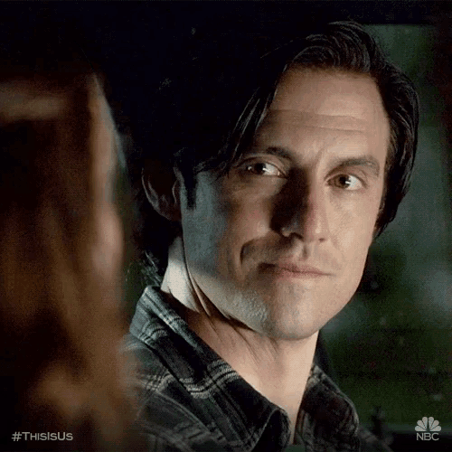 a man in a plaid shirt is smiling and looking at a woman .