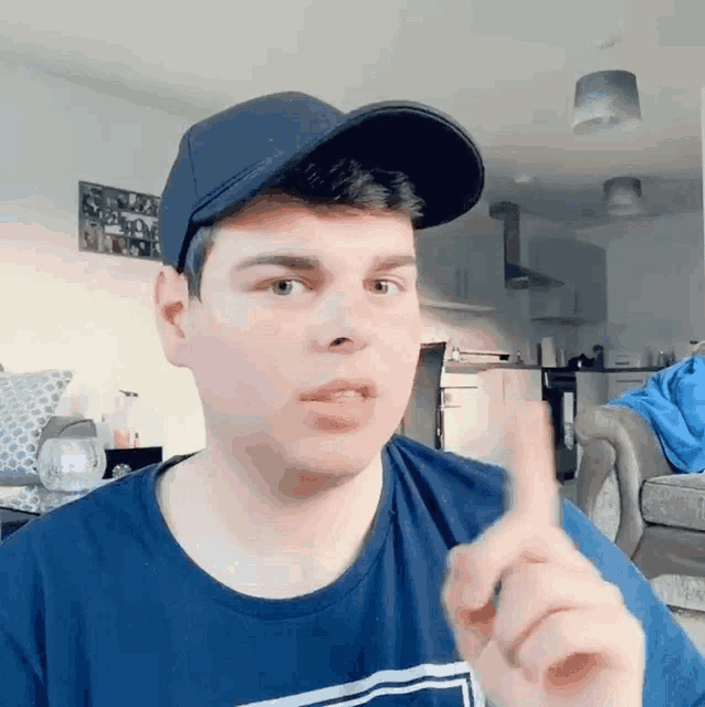 a man wearing a baseball cap and a blue shirt is pointing