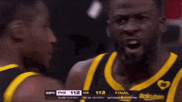 a man in a yellow and black basketball uniform is standing next to another man in a black and yellow basketball uniform .