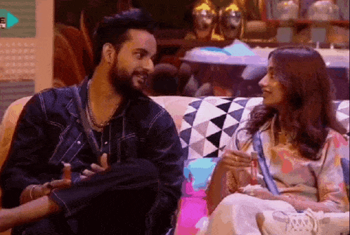 a man and a woman are sitting next to each other on a couch and talking to each other .