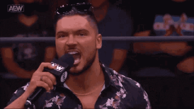 a man is talking into a microphone and saying `` tightest tits in the game '' in front of a crowd .