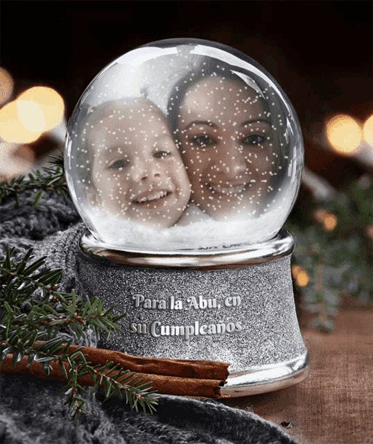 a snow globe with a picture of a woman and a child and the words para la abu en su cumpleanos