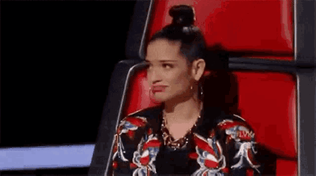 a woman is sitting in a red chair with her head resting on her elbow .