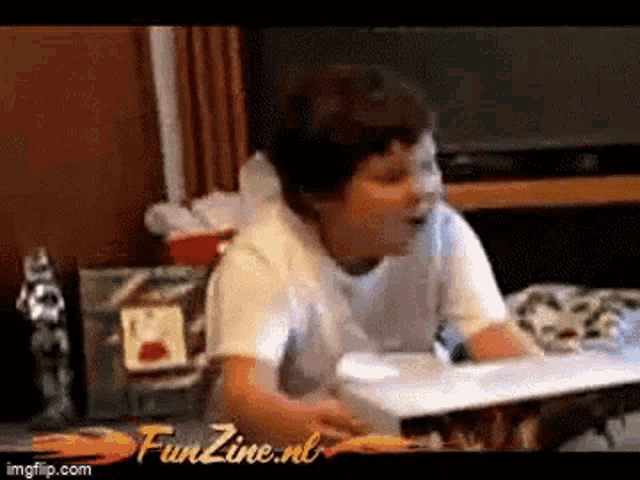 a young boy is playing a video game in a living room with the words funzine.nl on the bottom