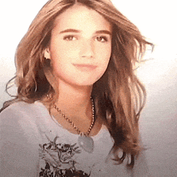 the girl is wearing a necklace and a white shirt with a cat on it .
