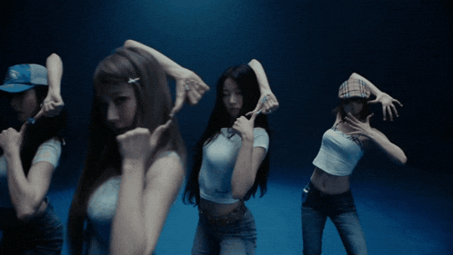 a group of young women are dancing in a dark room and one of them is wearing a plaid hat