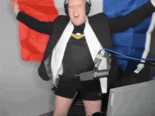 a man wearing headphones is standing in front of a microphone with his arms outstretched