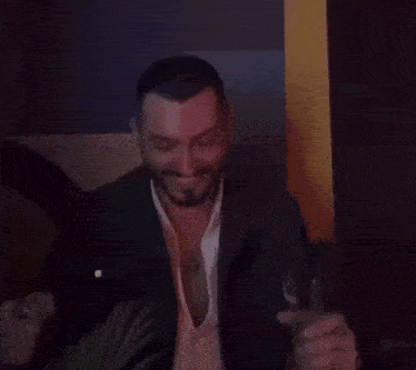 a man in a suit is holding a glass of wine