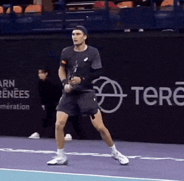 a man is playing tennis in front of a banner that says tere on it