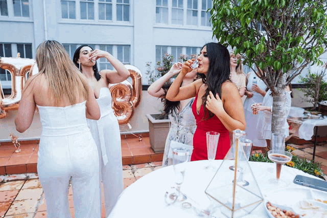 a woman in a red dress is drinking champagne