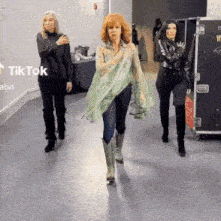 three women are walking down a hallway with a sign that says tik tok on it