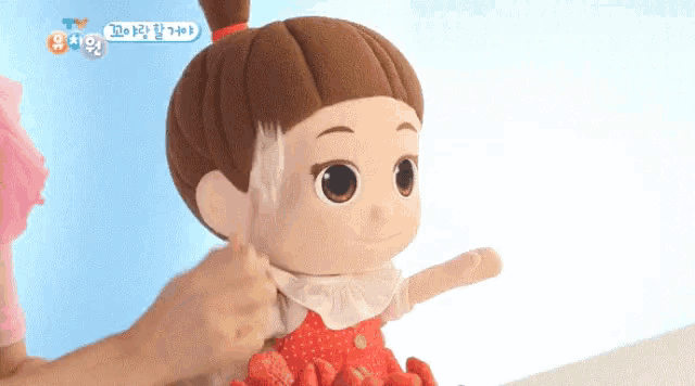a stuffed doll is being brushed by a child with korean writing on the bottom right