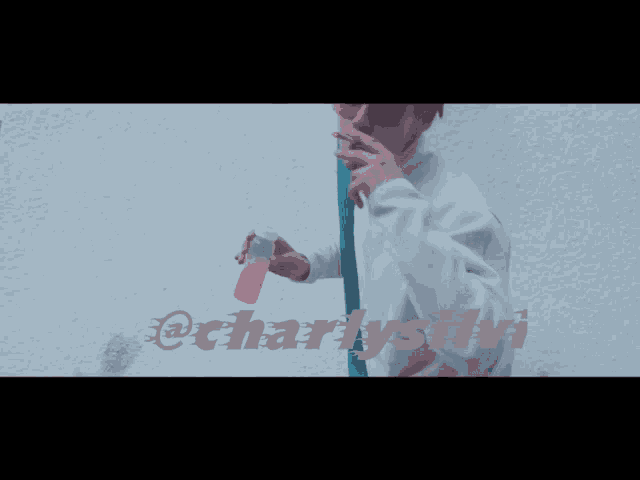 a man smoking a cigarette in front of a white wall with the words @charlysb on it