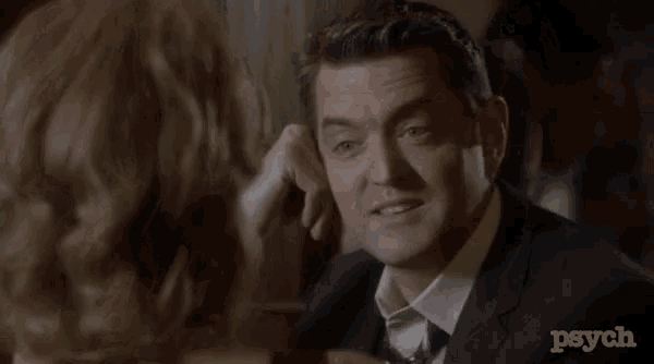 a man in a suit is being kissed by a woman in a room .