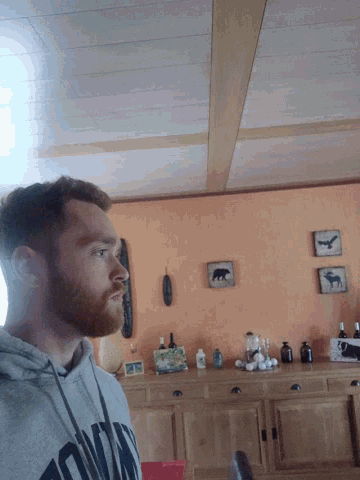 a man with a beard wears a grey sweatshirt with the word columbia on the front