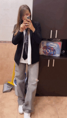 a woman taking a selfie in a bathroom with a box of kleenex behind her
