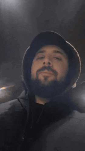 a man with a beard wearing a hat covering his mouth with his hands