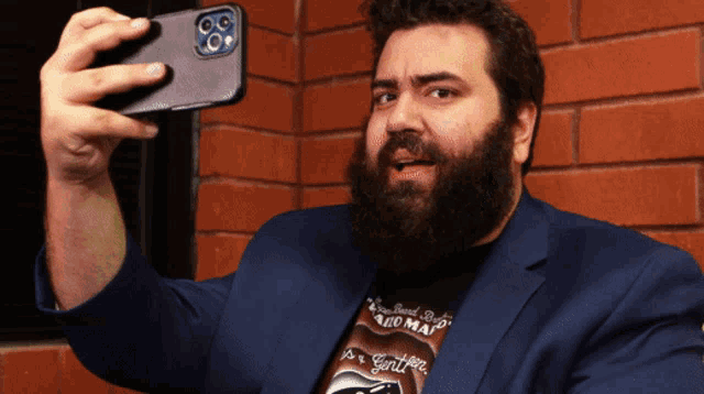 a man with a beard is taking a picture of himself with his phone