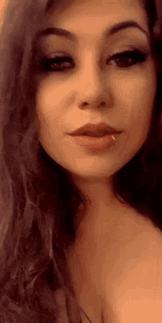 a close up of a woman 's face with a nose ring in her mouth .
