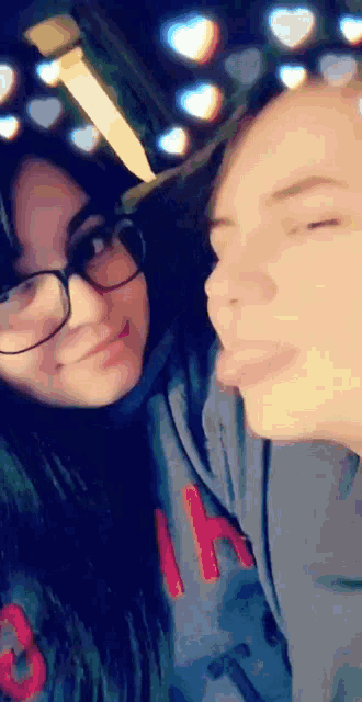a girl wearing glasses sticks her tongue out next to another girl