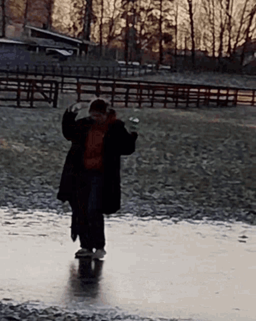 a person in a black coat is standing in a puddle of water