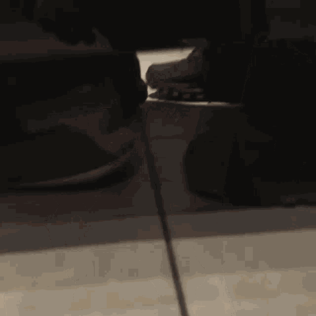 a person 's feet are shown in a blurry photo while standing on a tile floor .